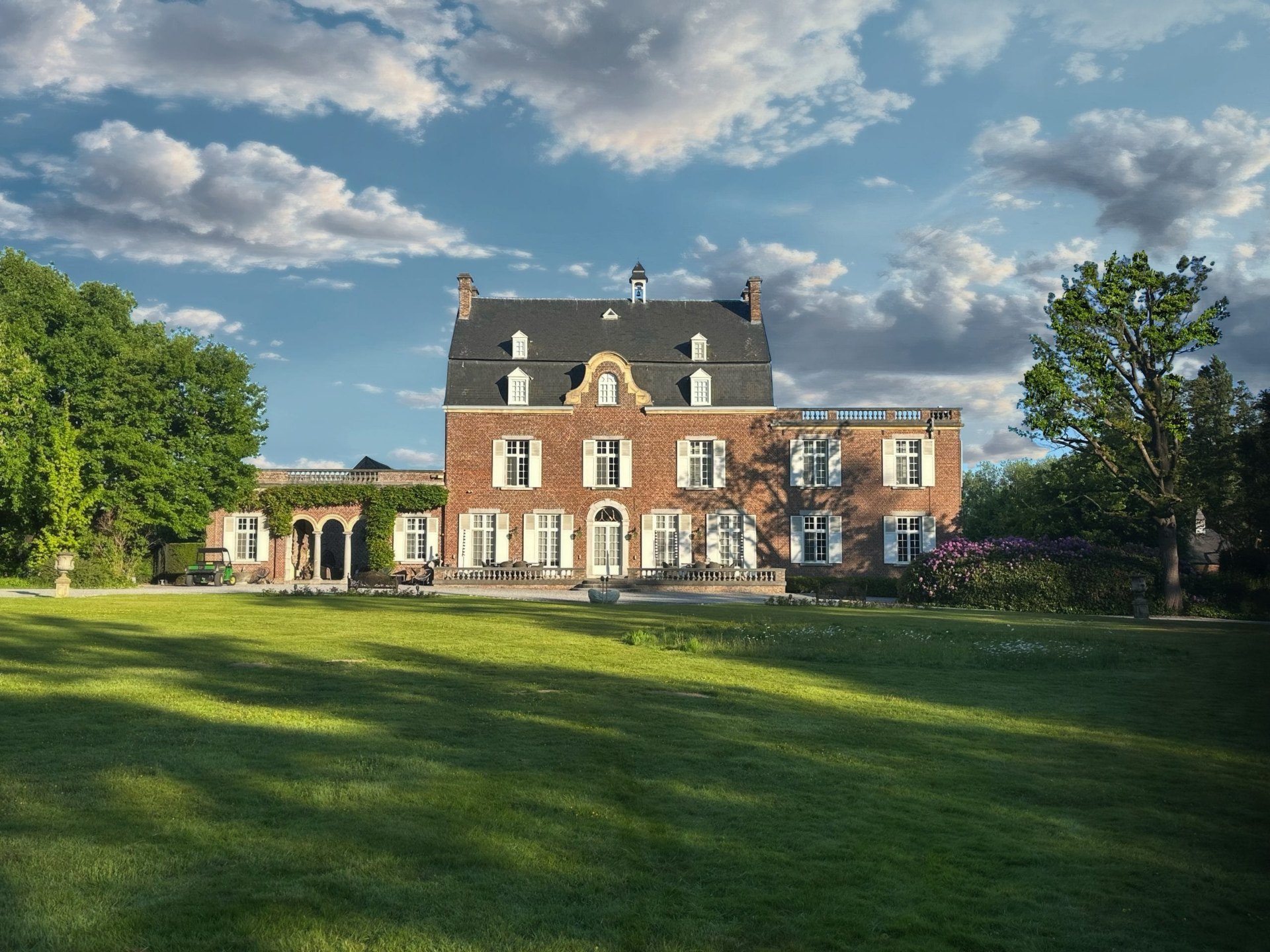 Historisch kasteel van Landgoed Ridderborn met roodbruine baksteen, witte luiken en weidse grasvelden in het gouden avondlicht.